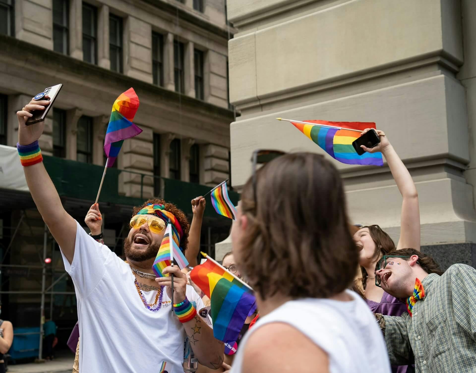 A group of people with pride flags outside on a city street
